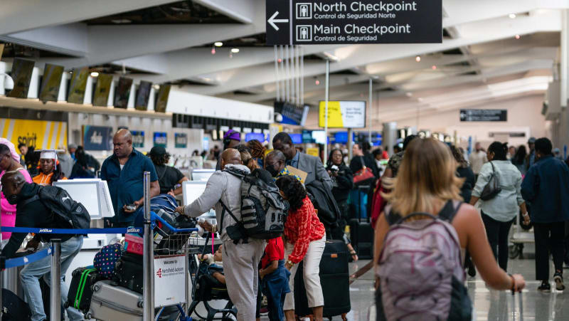 International travelers and families walking through a busy European airport terminal together