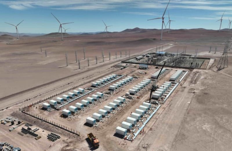 Large battery storage containers lined up at a wind farm construction site in Chile's Antofagasta desert region