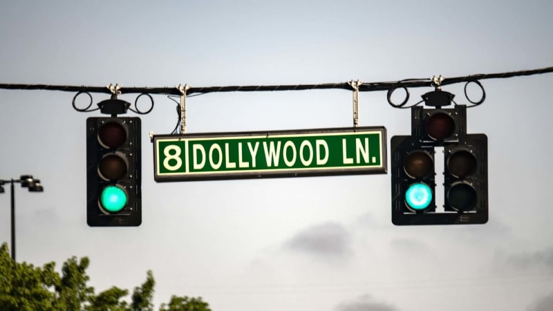 Electric vehicle charging at Dollywood theme park parking lot with mountains in background