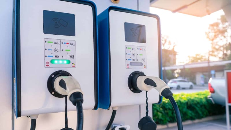 Electric vehicle charging at modern fast-charging station along sunny highway corridor