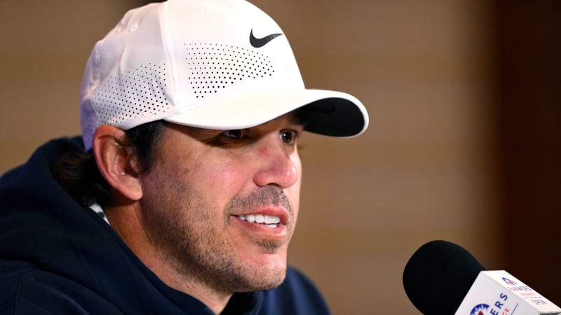 Brooks Koepka smiling at golf tournament wearing professional attire with Tiger Woods