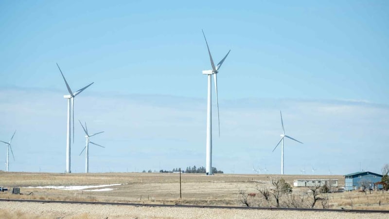 Modern wind turbines generating clean energy across rolling Wisconsin farmland under blue sky