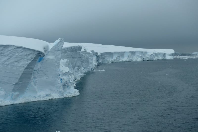 Research team operating hot water drilling equipment on white expanse of Thwaites Glacier Antarctica