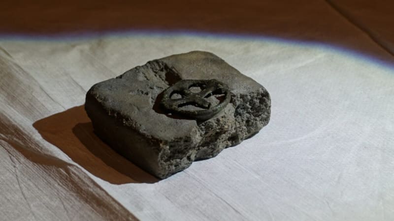 Ancient bronze wheel cross next to its thousand-year-old stone casting mold