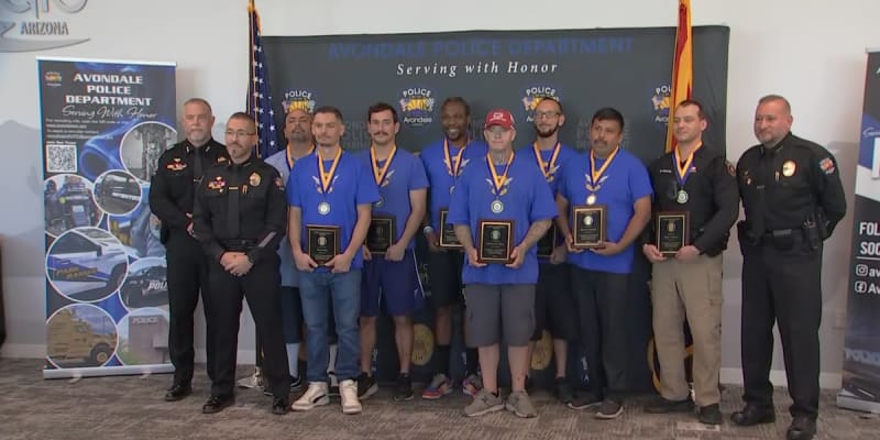 Nine good Samaritans standing with Avondale police officers holding award plaques and medals