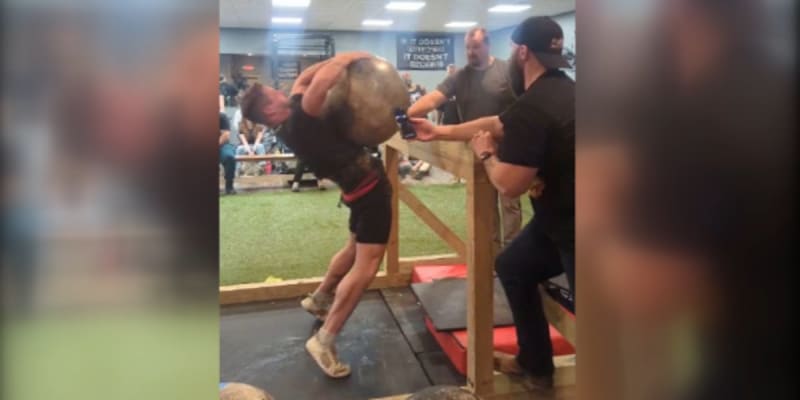 Strongman competitor Matt Sowers lifting massive atlas stone over four-foot bar at competition