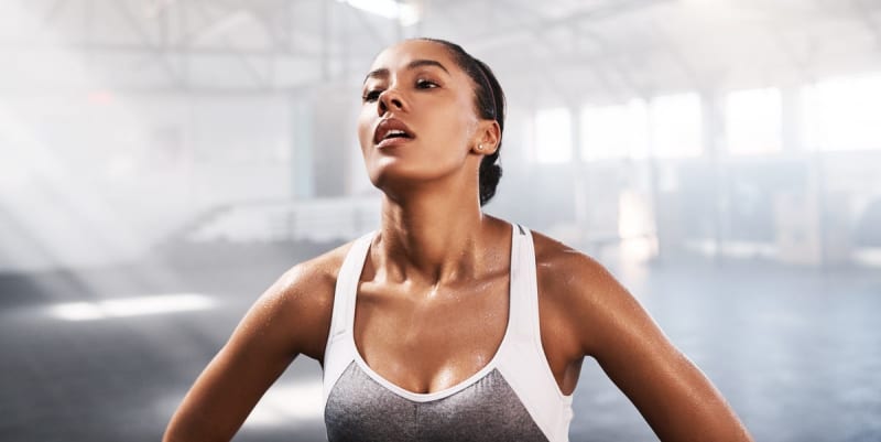 Beginner lifting light dumbbells in bright gym with confident smile and proper form