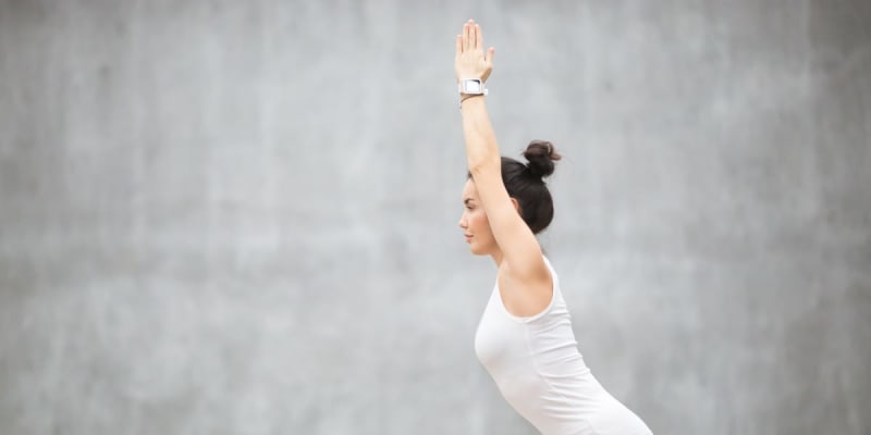 Person practicing gentle stretching exercises while seated in a chair during yoga session