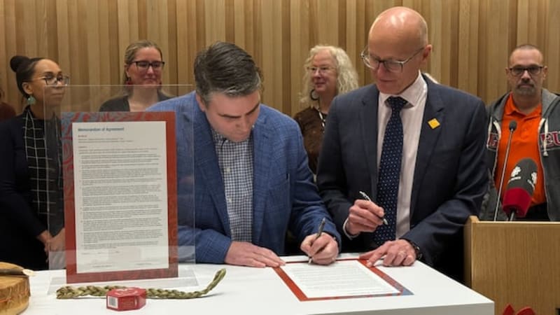 ** Union president Kyle Ross and college president Fred Meier sign agreement at table