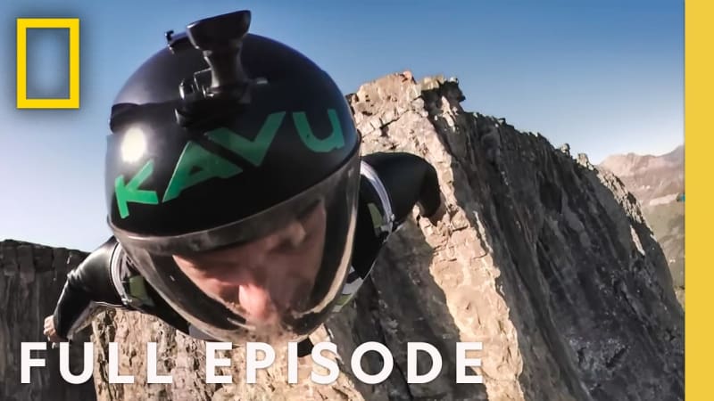 BASE jumper soaring through blue sky above dramatic mountain landscape, arms outstretched in flight, capturing freedom and joy