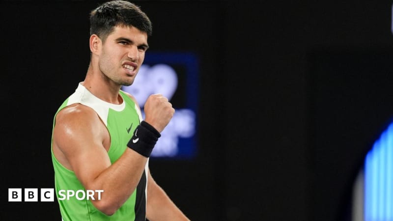 Carlos Alcaraz smiling on court during his Australian Open victory wearing white tennis gear