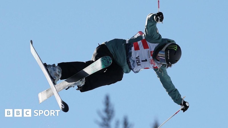 British freestyle skier Zoe Atkin performing aerial trick high above halfpipe at competition
