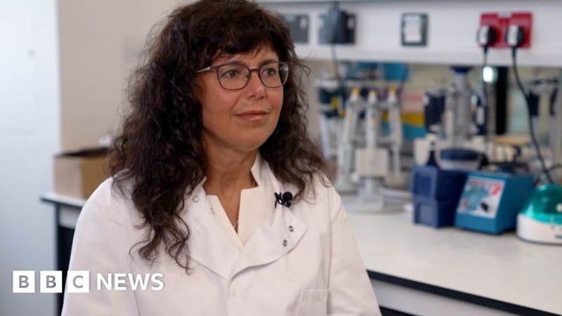 Medical researcher holds small blood sample vial in laboratory testing facility for Alzheimer's detection study