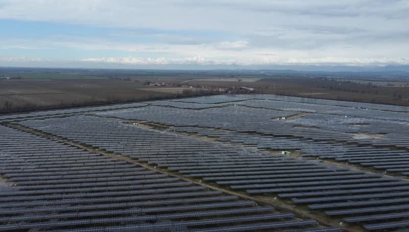 Aerial view of solar panel arrays covering Italian countryside under bright Mediterranean sunshine