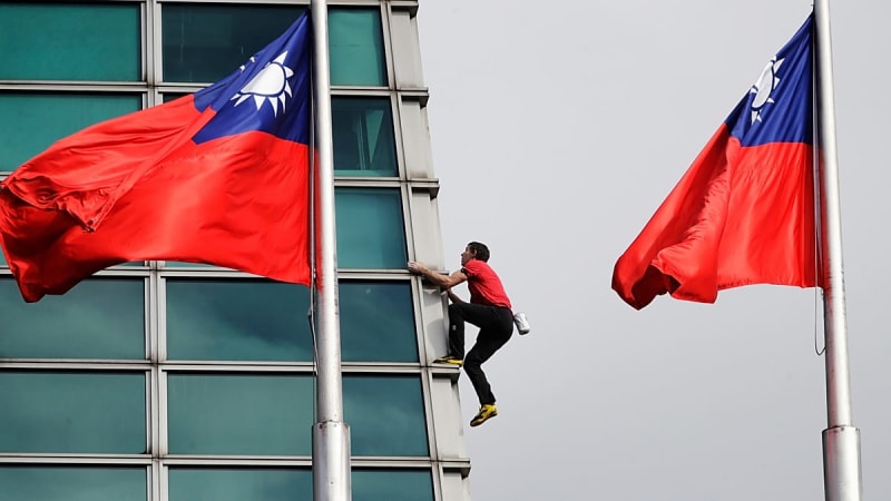 Alex Honnold climbing the exterior of Taipei 101 skyscraper using small metal footholds without ropes