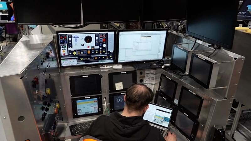 Engineers testing virtual train systems on computer screens inside Train Zero laboratory facility