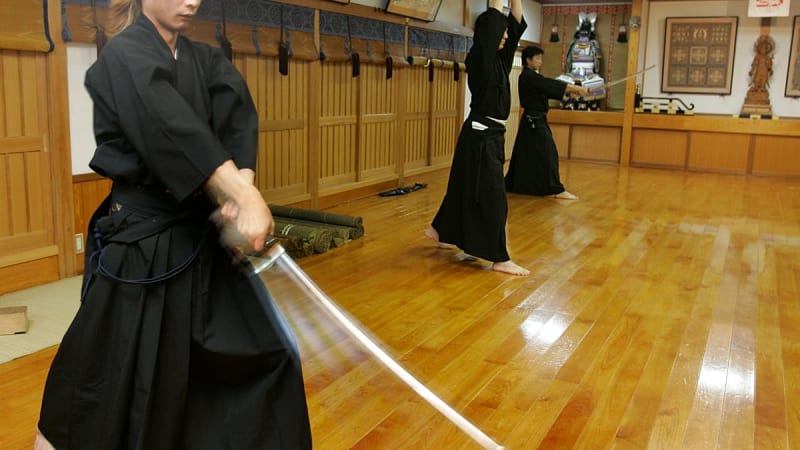 Japanese master swordsmith Akihira Kawasaki forging traditional katana blade in workshop with glowing steel