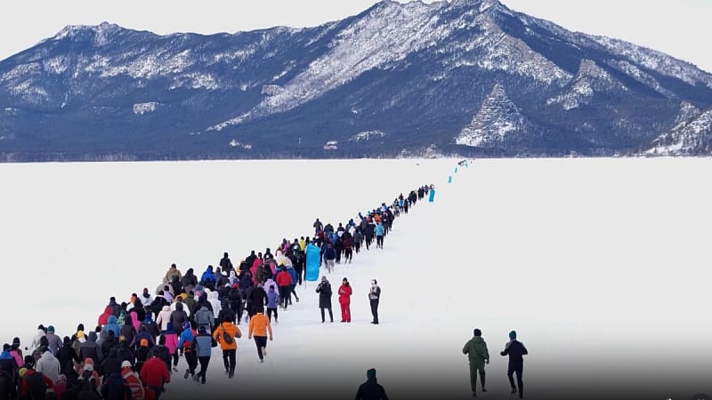 Large group of runners racing across frozen white lake surface in Kazakhstan winter