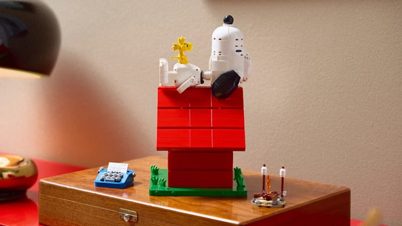 Lego Snoopy sitting on red doghouse with Woodstock and campfire set pieces