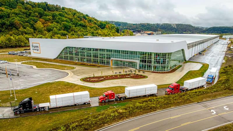 Large rectangular Form Energy iron-air battery enclosures arranged in rows in an open field