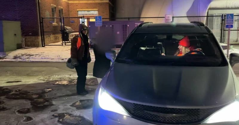 Volunteers in orange vests outside building helping recently released detainees with phones and transportation