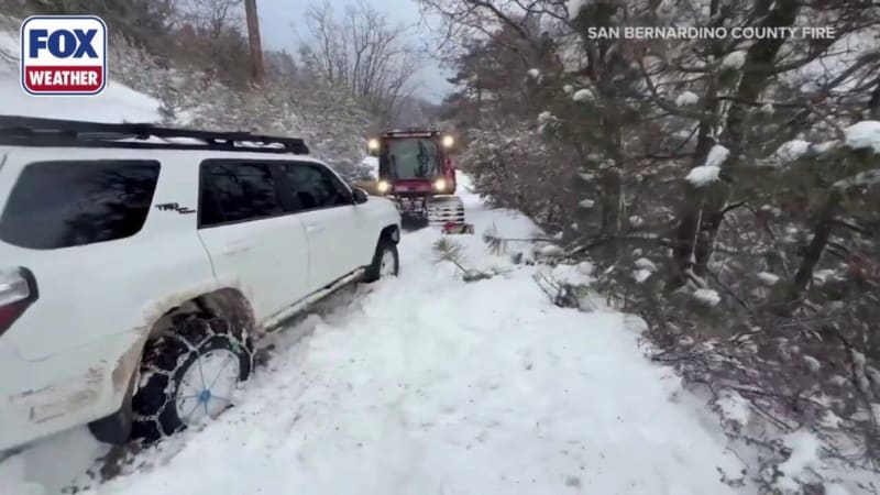 San Bernardino County Fire Department snowcat vehicle navigating through deep mountain snow during rescue operation
