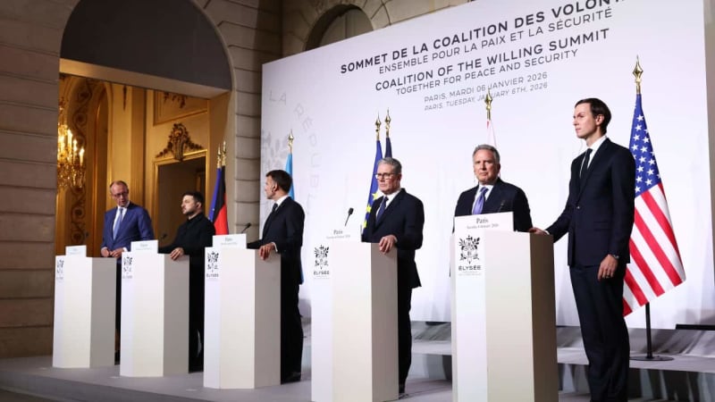 International leaders shaking hands at Paris summit, flags of Coalition of the Willing nations displayed prominently in background