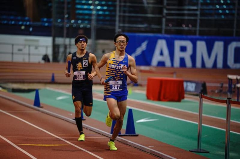 William Thu running on indoor track during 800 meter race at Metropolitan Championship