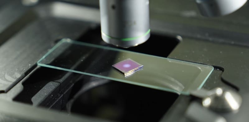 Glass slide with metallic nanoparticle coating shown under microscope creating colorful light patterns for water testing