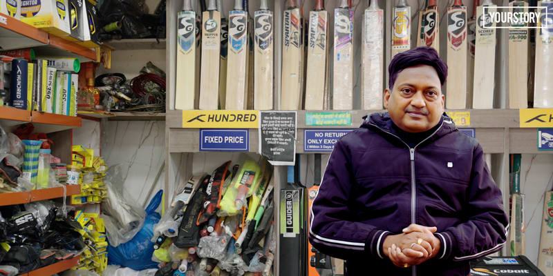 Sports shop owner in India threading strings through badminton racket on professional machine