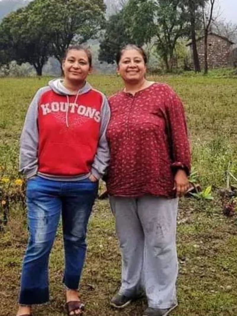 Two sisters standing in their green organic amla farm in Dehradun India hillside