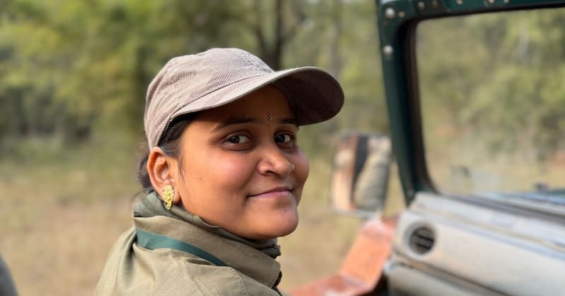 ** Female naturalist scanning forest floor for animal tracks during early morning safari preparation