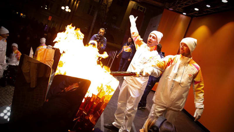 Paralympic skier Giacomo Bertagnolli lighting ceremonial brazier in crowded Italian plaza at night
