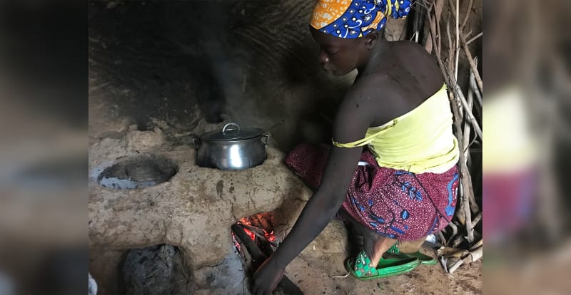 Woman cooking on improved clay cookstove in rural Cameroon village home