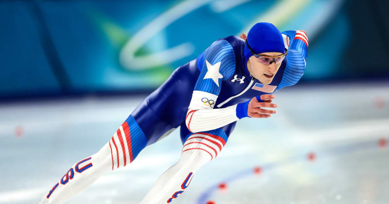 Jordan Stolz racing in blue Team USA speedskating suit on ice track in Milan