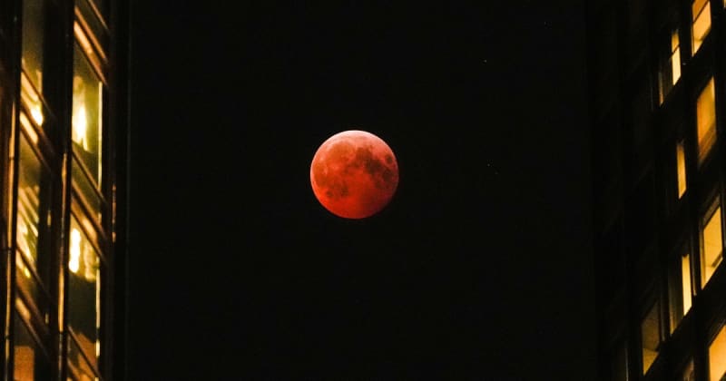 Deep red blood moon glowing against dark night sky during total lunar eclipse