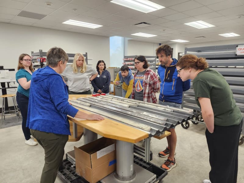 Teachers gathered around ocean core samples examining data at Texas A&M Gulf Coast Repository