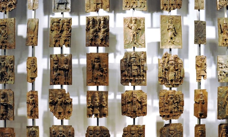 Historic Benin Bronze artifacts including sculptures and commemorative heads displayed in museum setting