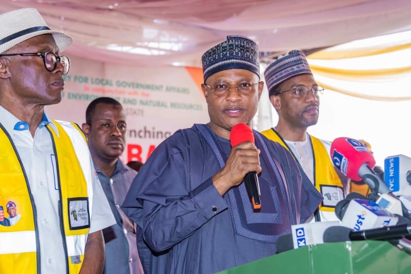 Nigerian sanitation workers in protective gear cleaning urban streets in Kaduna State