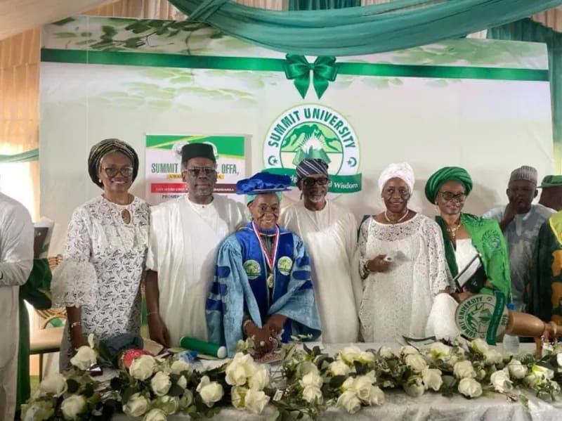 Elderly Nigerian woman in traditional dress smiling at university ceremony with family members