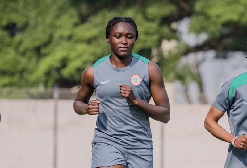 Rinsola Babajide in Nigeria's green jersey celebrating with WAFCON trophy held high