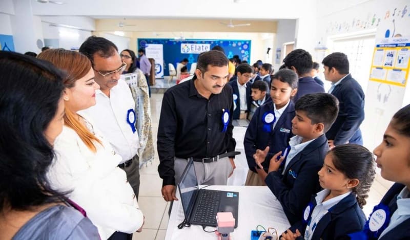 Students demonstrating homemade robots and artificial intelligence projects at school technology exhibition