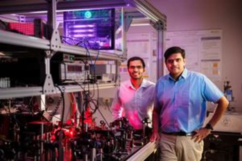 Two scientists standing in modern optics laboratory with AI-assisted research equipment at Sandia National Laboratories