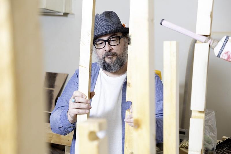 Ryan Richard standing beside recycled materials in gallery studio space at University of Saskatchewan