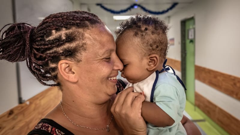 Mother Abigail Hendricks smiling while holding her healthy nine-month-old baby Hayden at home