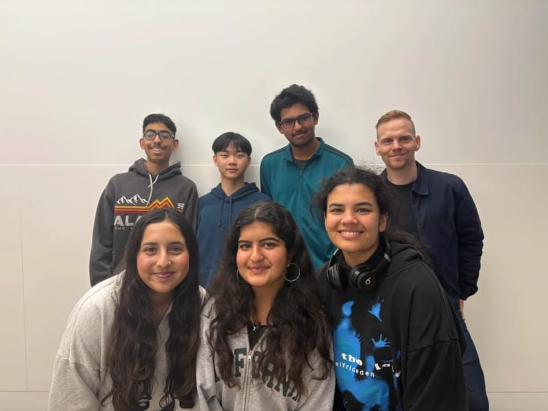 Students coding together at computers during a youth technology hackathon competition event