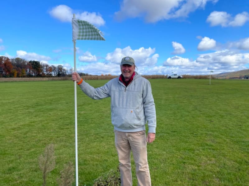 Penn State Professor David Huff standing in green turfgrass research field holding grass samples