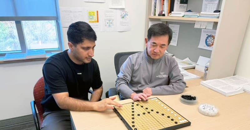Two researchers setting up a Go board game, demonstrating the ancient strategy game that inspired modern cooling technology breakthrough
