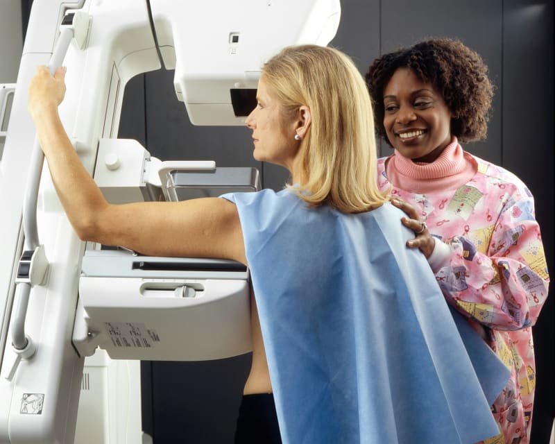 Medical professional reviewing mammogram images on computer screen with AI assistance overlay