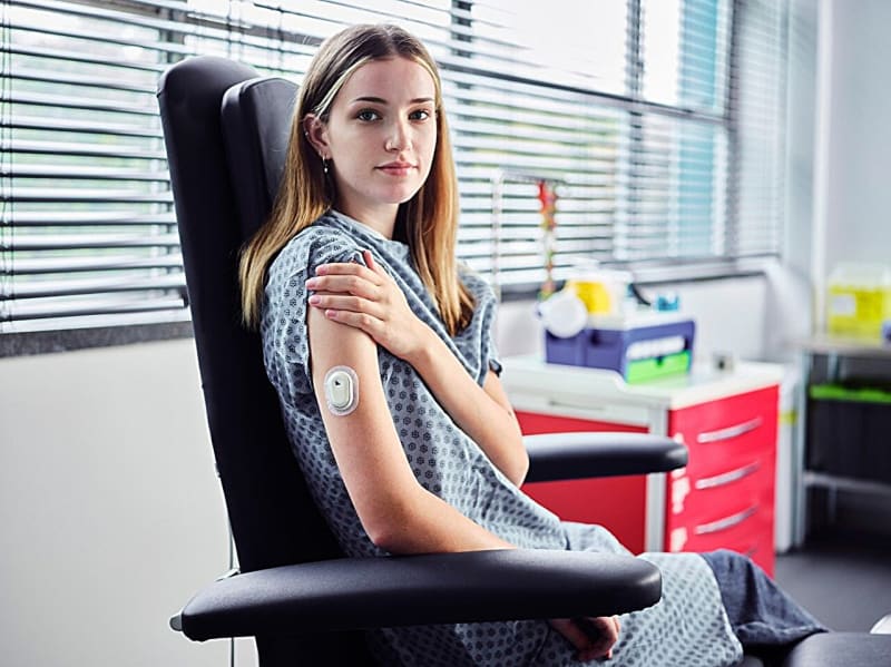 Small medical patch with microneedles worn on patient's arm for continuous drug monitoring